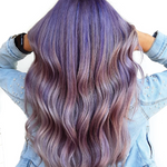 Person with wavy, multicolored hair wearing a denim jacket.