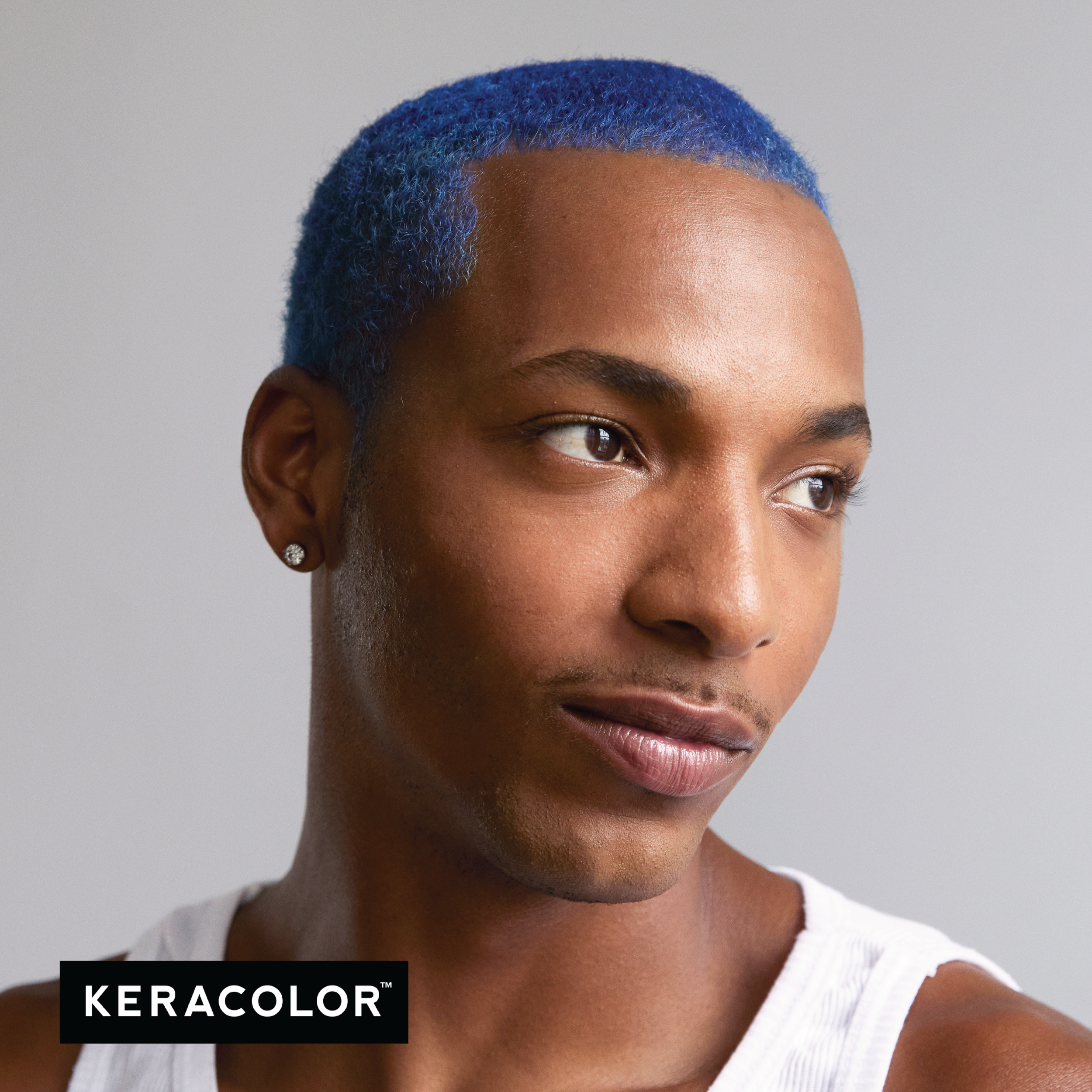 Person with blue hair wearing a white tank top on a gray background, with Keracolor logo.