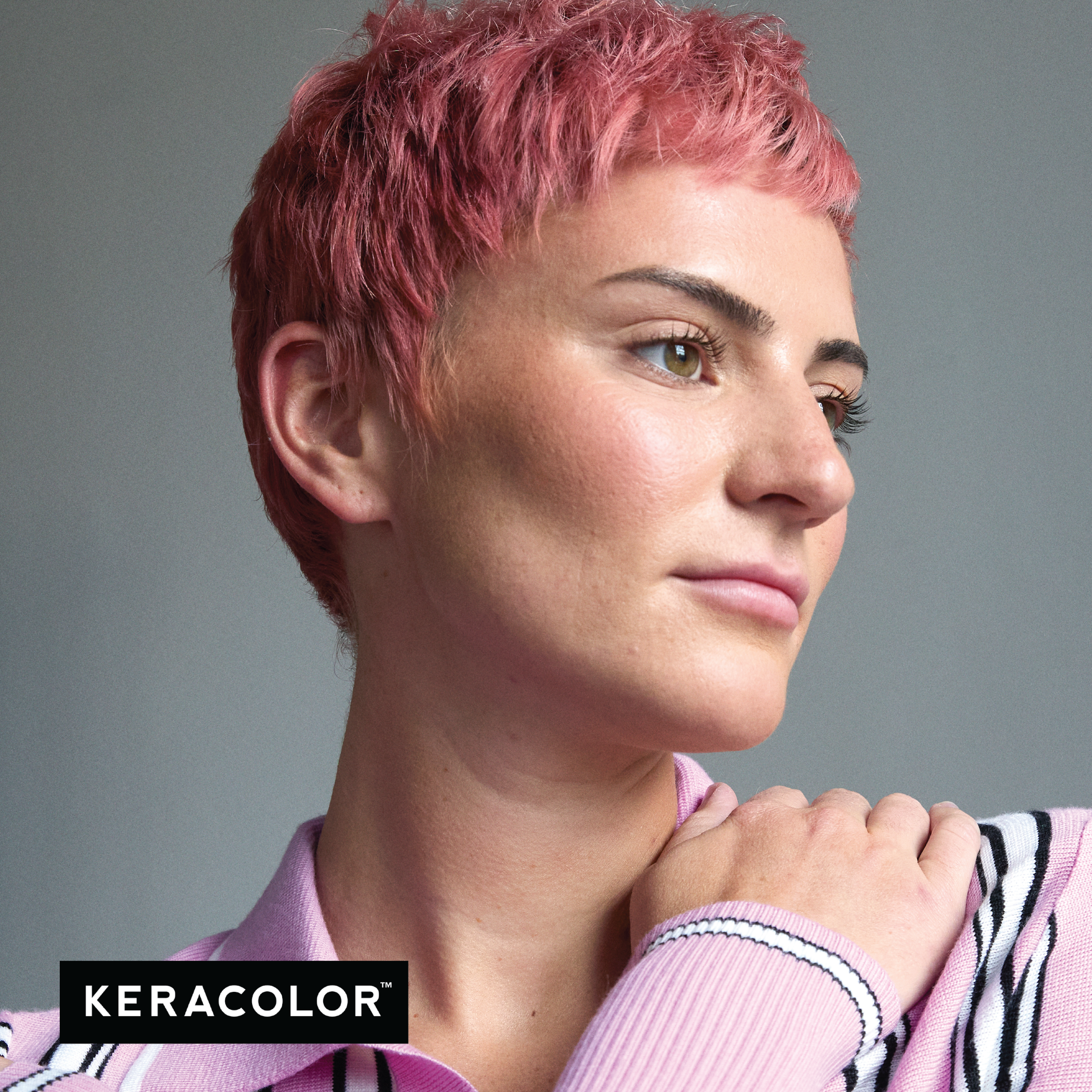 Person with pink hair wearing a pink sweater, with Keracolor logo.