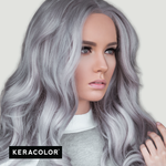 Woman with silver hair styled in wavy locks, wearing a gray sweater, with Keracolor logo.